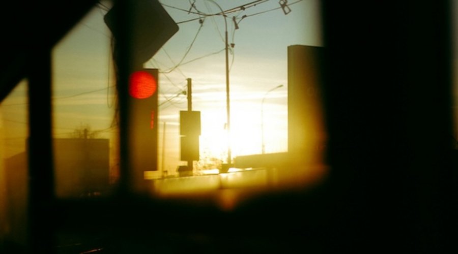 Straßenszene bei Sonnenuntergang mit rotem Verkehrsschild im Vordergrund und stä