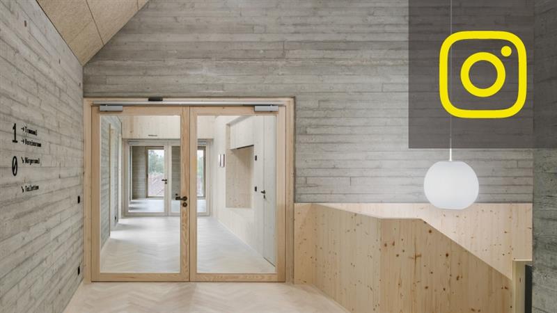 Heller Betonbauinnenraum mit Holztüren, Wandbeschriftungen und einem gelben Inst